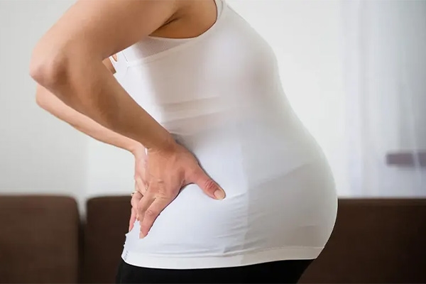 A pregnant woman holding her back in pain during pregnancy