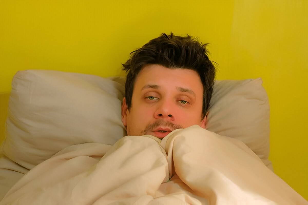 A man waking up in the morning tired and shaking