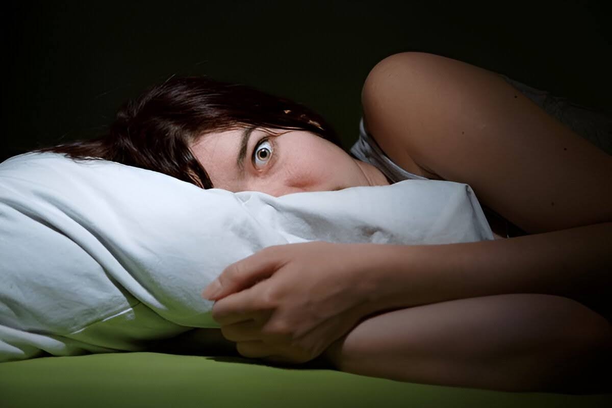 A young woman on the bed with her eyes opened suffering from sleep anxiety