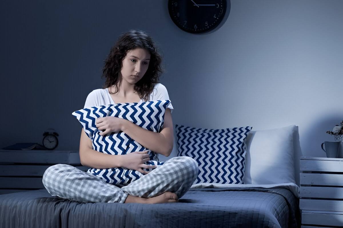A woman sitting on her with a pillow, unable to sleep, emphasizing sleep deprivation