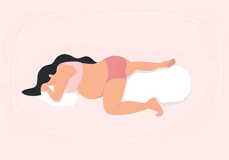 A pregnant woman lying on her stomach with pillows under her head and between her legs