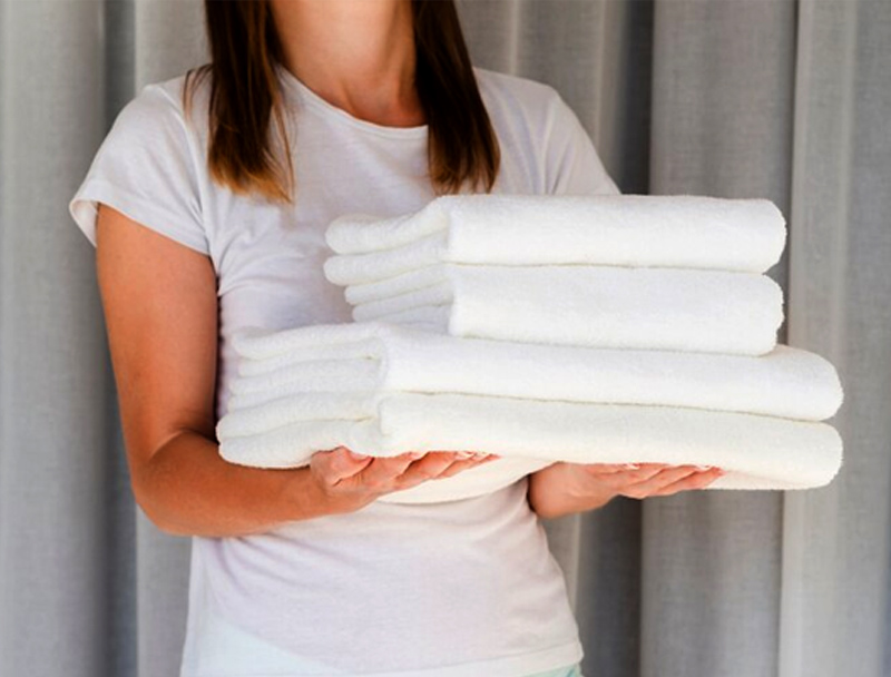 A woman holding different sizes of white towel.