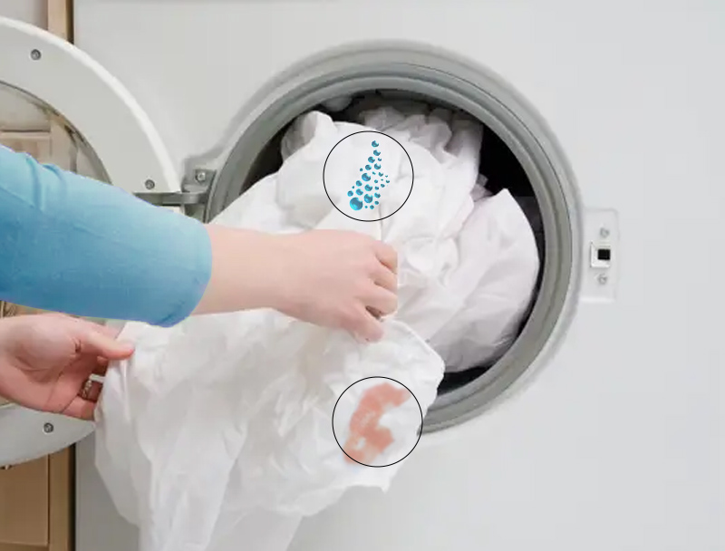 A person putting a white fabric in the front load washer for cleaning.