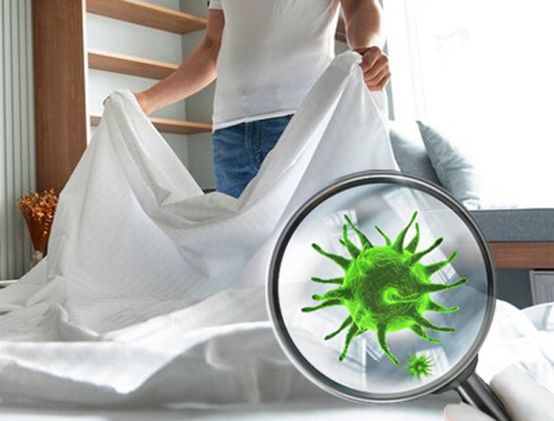 An image showing a man holding a white sheet with bacteria icon on it depicting fabric germs.